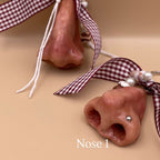 Two dog nose-shaped keychains with ribbons on a beige background